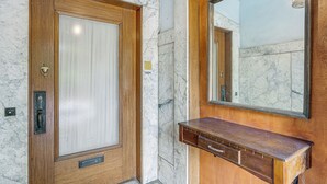 Una puerta de madera con un panel de vidrio, una pared de mármol y un tocador de madera con un espejo.