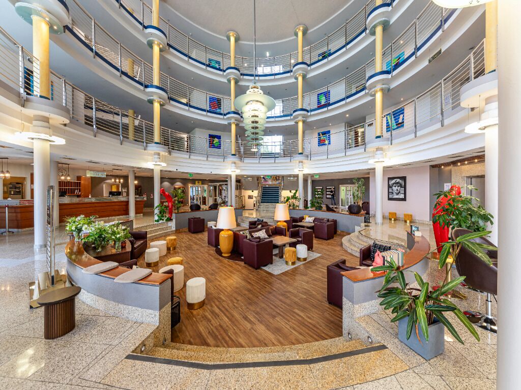 Unwind beneath soaring atrium lights in a stylish lounge.