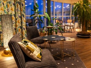Ein gemütlicher Sitzbereich mit Sofa, Sessel, einem kleinen runden Tisch und einer Topfpflanze.