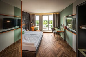 Une chambre d’hôtel moderne, dotée d’un grand lit, d’un bureau, d’une télévision et offrant une vue sur l’extérieur.