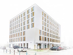 Ein modernes Gebäude mit weißer Fassade und vielen Fenstern.
