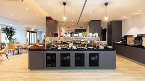 Een moderne keuken met een centraal eiland, verlichting bovenin en een zithoek met stoelen en tafels.