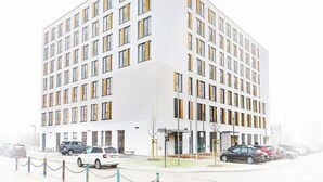 Een modern gebouw met een witte gevel en veel ramen.