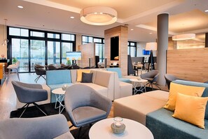 Ein stilvoller Lounge-Bereich mit Sitzgelegenheiten, einem Kamin und großen Fenstern für natürliches Licht.