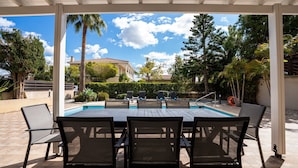 Eine Außenpatio mit Pool, umgeben von Stühlen und Palmen.