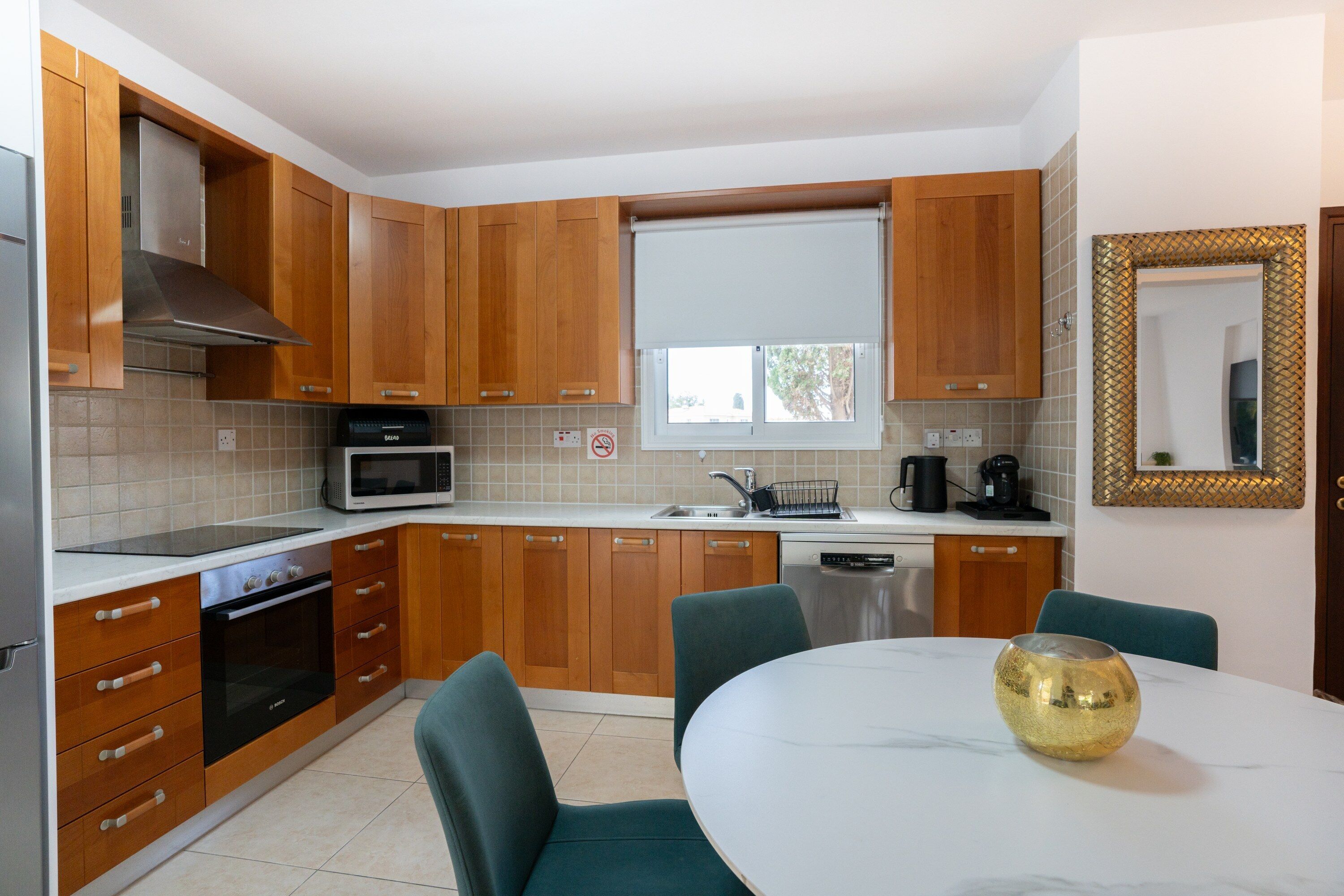 A modern kitchen with wooden cabinets, a microwave, a sink, and a dining table with chairs.