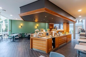 Ein modernes Café mit einer zentralen Holztheke, Sitzbereich und Blick ins Freie.
