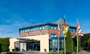 Ein modernes Gebäude mit Backsteinfassade, großen Fenstern und einem überdachten Eingangsbereich.