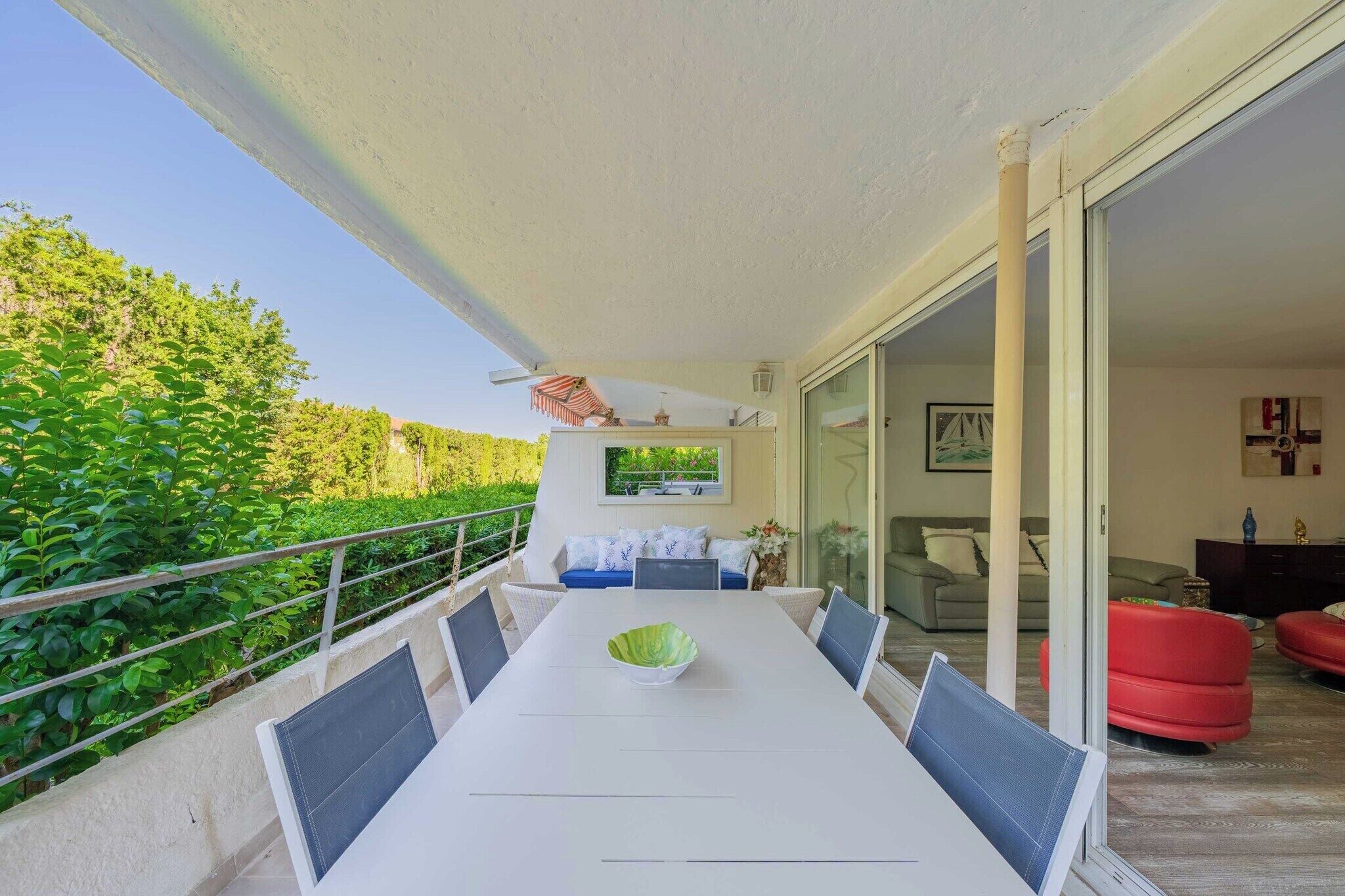 Un balcon avec une table à manger, des chaises et un saladier vert.