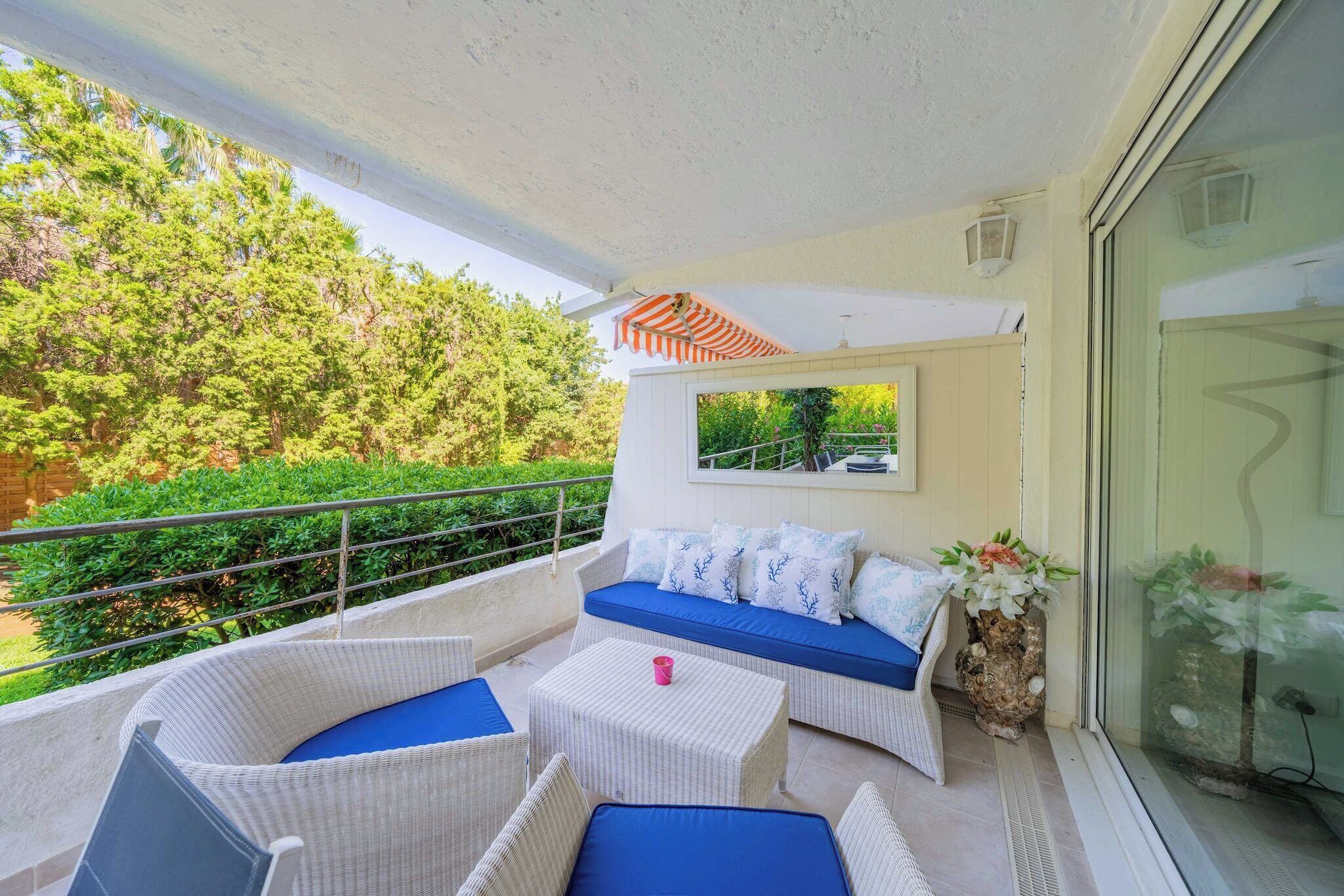 A balcony with wicker furniture, a blue cushioned sofa, and a small table.