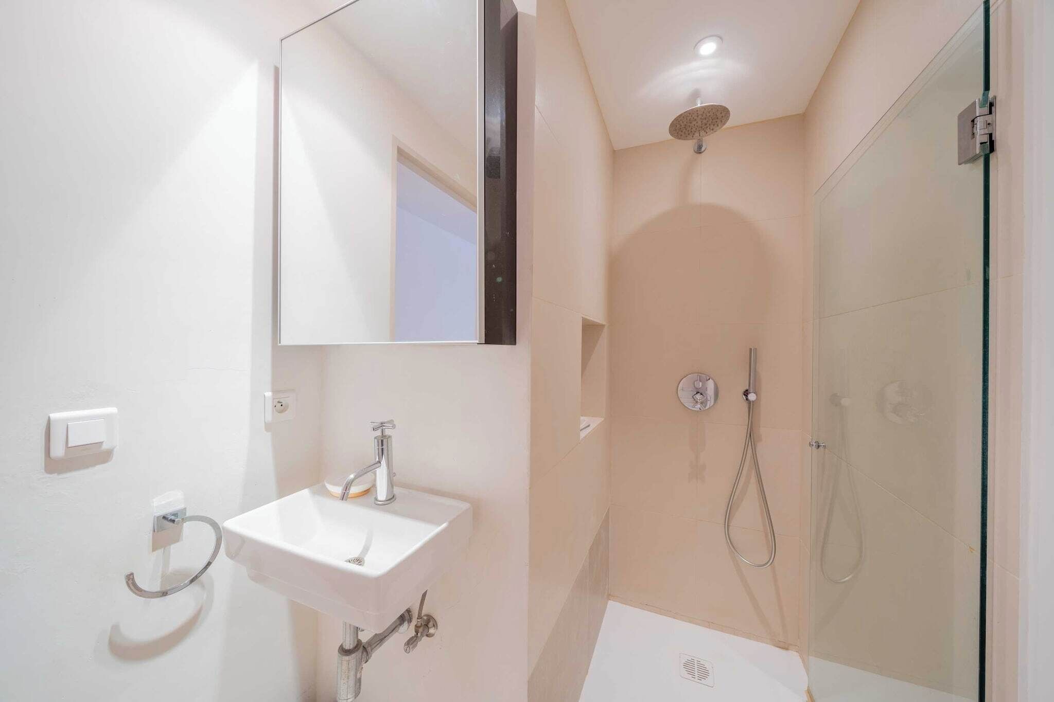 A modern bathroom with a sink, mirror, and shower.