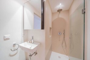 Un baño moderno con lavabo, espejo y ducha.