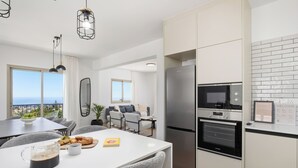 Een moderne keuken met een inbouwoven, een koelkast en een eethoek met een tafel en stoelen.