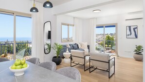 Een ruime woonkamer met balkon, een eettafel met appels en een bank met kussens.
