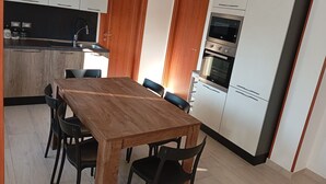 Een moderne keuken met een houten eettafel en stoelen, witte kasten en inbouwapparatuur.