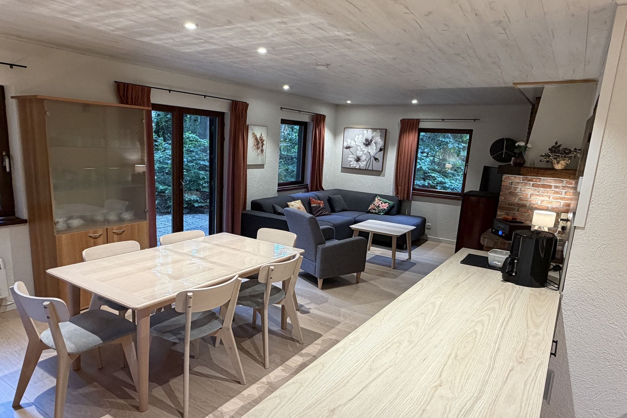 Ein modernes Wohnzimmer mit einer Couch, einem Esstisch und Stühlen. Ein Fernseher und ein Kamin sind ebenfalls vorhanden.