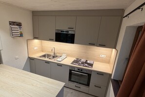 A compact kitchen with a built-in oven, a sink, and a microwave.
