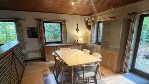 A dining area with a wooden table and chairs, a kitchen with a sink and cabinets, and a deer head mounted on the wall. - Charming Holiday Base in the Ardennes for 8 (Rendeux - Beffe)
