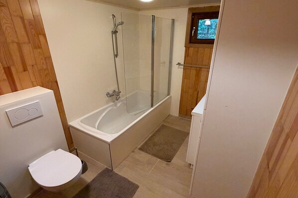 A bathroom with a bathtub, toilet, and shower enclosure.