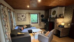 A living room with a sofa, armchair, and fireplace. - Charming Holiday Base in the Ardennes for 8 (Rendeux - Beffe)