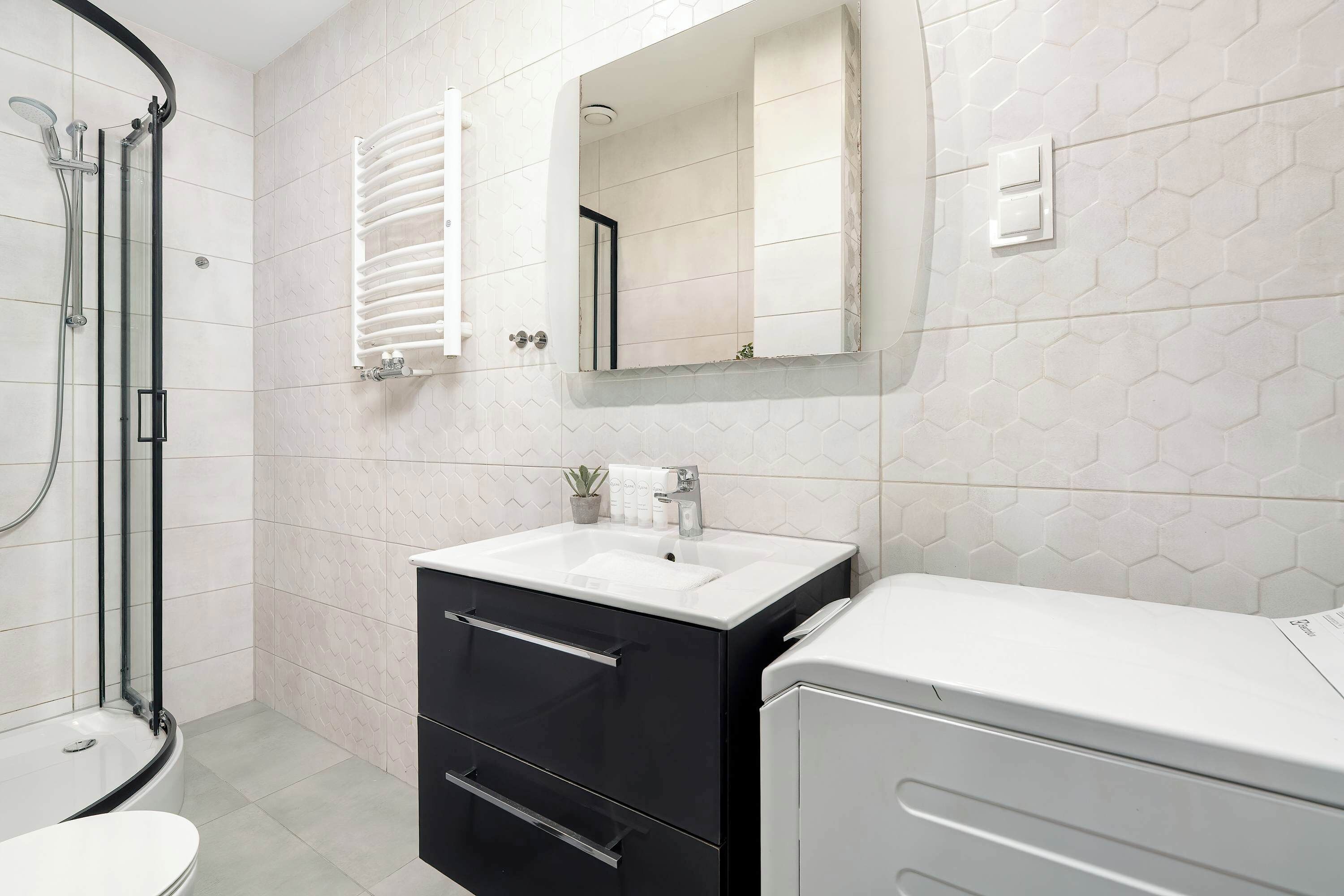 A bathroom with a shower, a sink, a mirror, and a cabinet.