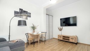 Una sala de estar moderna con un sofá, un escritorio, una silla, un televisor y un aparador.