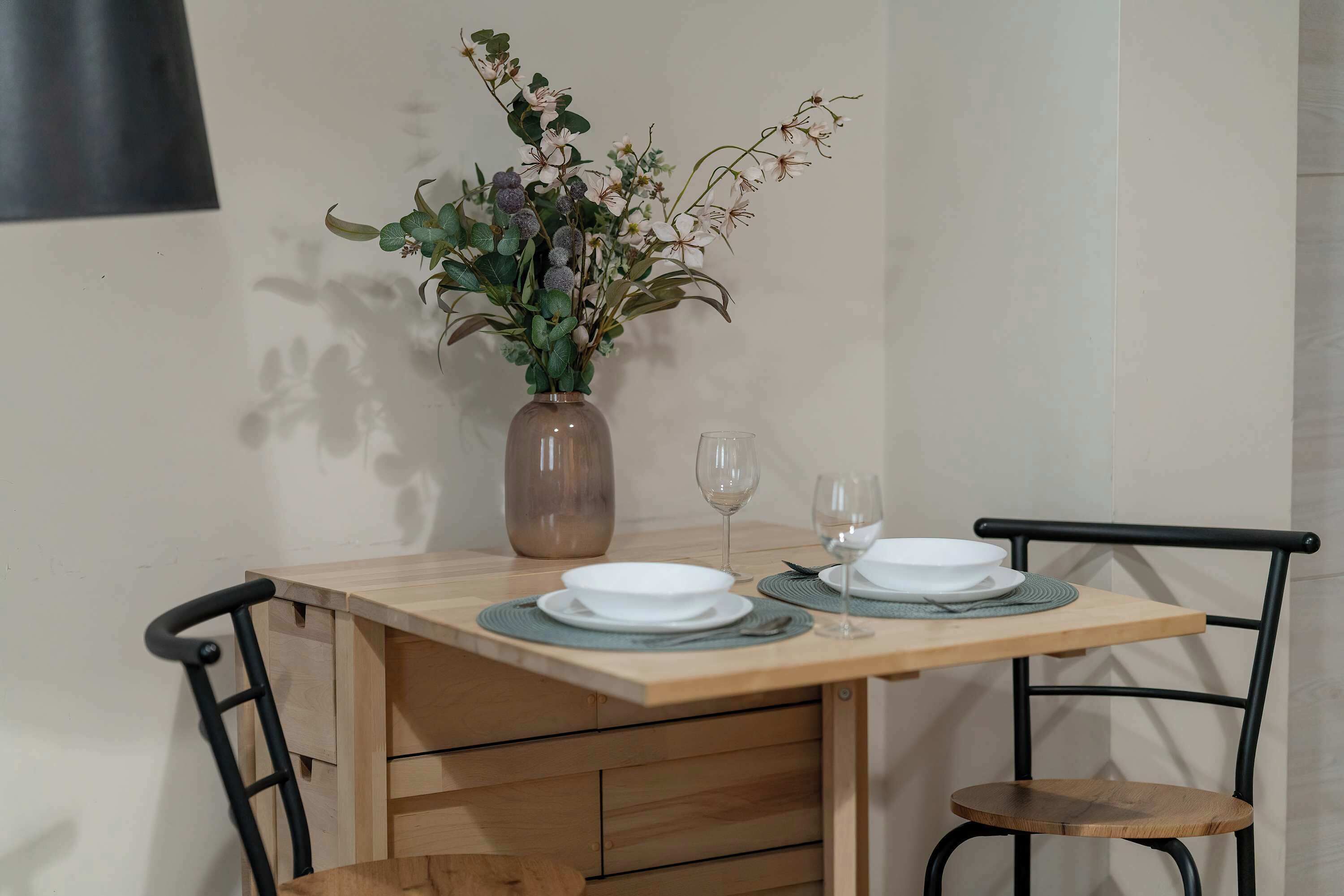 A dining table with two plates and a vase of flowers.