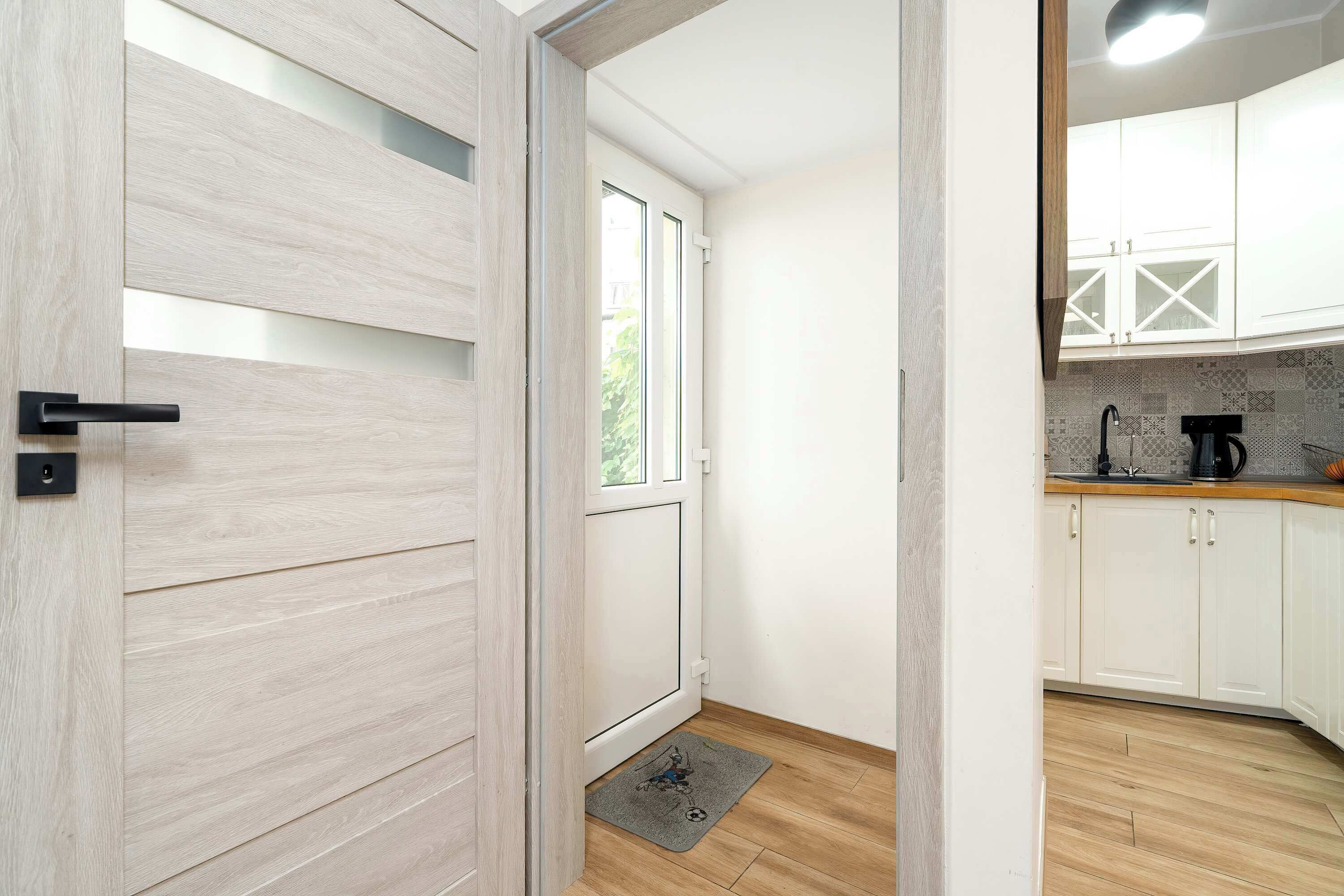 A modern kitchen with white cabinets, a coffee machine, and a wooden floor.