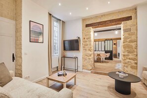 Un salon moderne avec un mur en pierre, un téléviseur à écran plat, une table basse en bois et une table ronde noire.