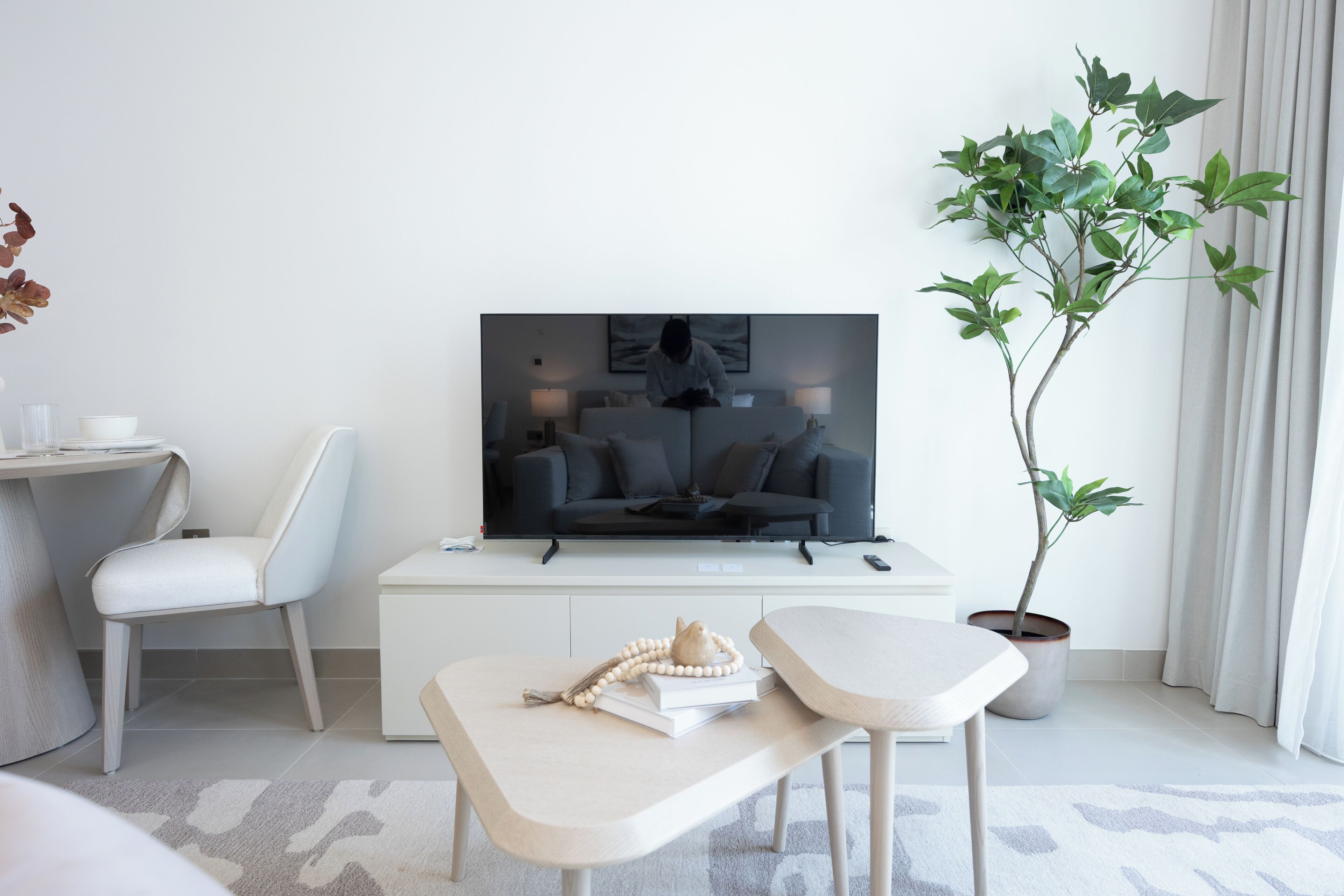 Ett modernt vardagsrum med en platt-TV, en soffa, ett soffbord, en krukväxt och en stol.