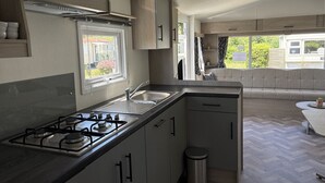 A compact kitchen with a gas stove, sink, and cabinets. - De Zeeuwse Parel Vacation Park - Sunset Comfort (Scherpenisse)