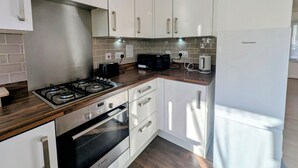 A modern kitchen with white cabinetry, a Bosch oven, a microwave, and a Frigidaire refrigerator. - Modern 2BDR Garden Home With Parking and WiFi (Greater London)