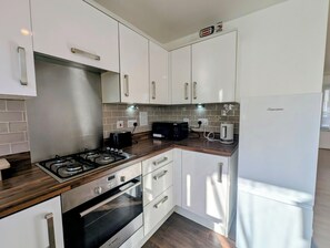 A modern kitchen with white cabinetry, a Bosch oven, a microwave, and a Frigidaire refrigerator. - Modern 2BDR Garden Home With Parking and WiFi (Greater London)