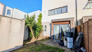 A residential property with a small garden, a wooden fence, and a white building with a garage. - Modern 2BDR Garden Home With Parking and WiFi (Greater London)