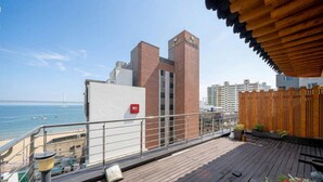 A rooftop terrace with a view of the sea and a bridge, a wooden fence, and a building with 'HOUND HOTEL' signage. - Busan LaMer Gwangan Stay (Busan)
