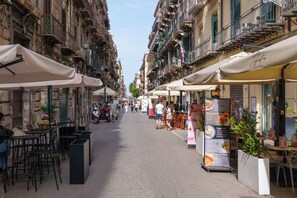 A narrow street lined with outdoor cafes and restaurants, featuring tables and chairs, and a variety of storefronts. - Suite Radici  Holiday Home: Elegance and Tradition in the Heart of Palermo (Palermo)