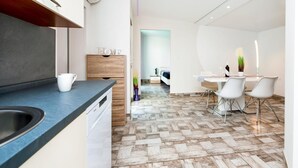 A modern kitchen with a built-in oven, a dining area with a white table and chairs, and a herringbone-patterned floor. - 2 bedroom awesome apartment in Rovinj (Rovinj)