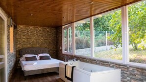 Un dormitorio con cama, bañera y ventanas amplias.