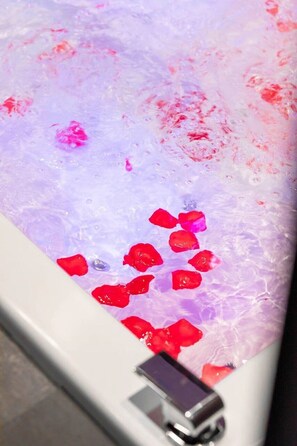 A bathtub with rose petals and a mobile phone. - The Secret of the Dukes - Private Spa Suite (Dijon)