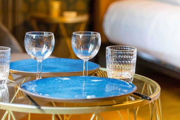 Una mesa con platos azules y vasos transparentes, sobre una base dorada de metal.