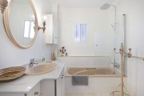 A bathroom with a sink, mirror, bathtub, and shower.