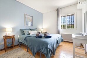 A bedroom with a bed, bedside tables, a window with curtains, and a painting on the wall.