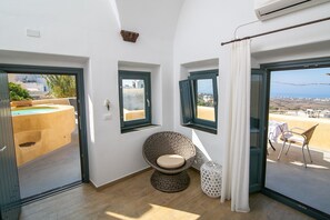 Une pièce comprenant un fauteuil rond en osier, une petite table et une vue sur la mer par une fenêtre.