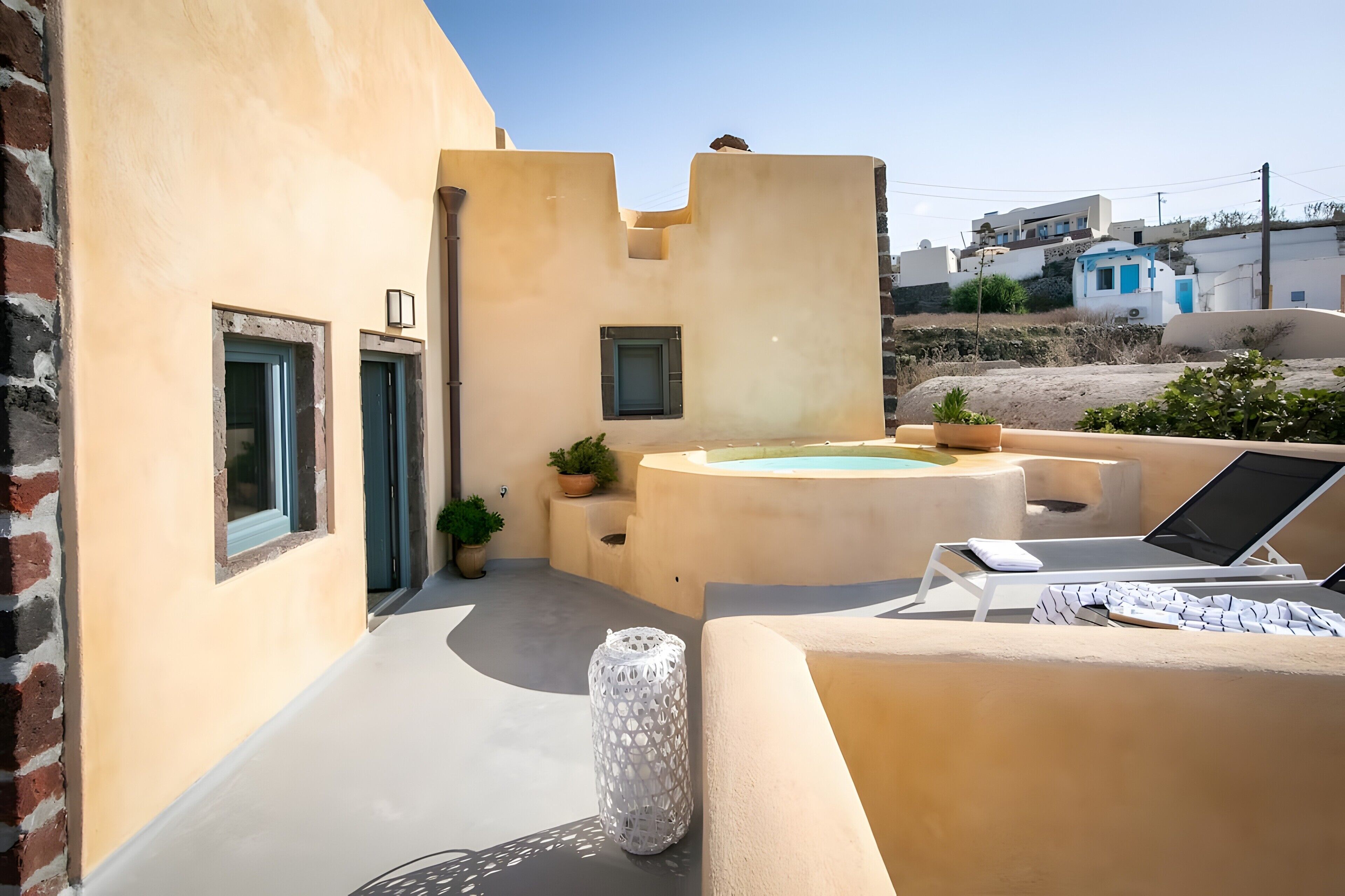 A sunlit outdoor area with a pool, lounge chairs, and potted plants.