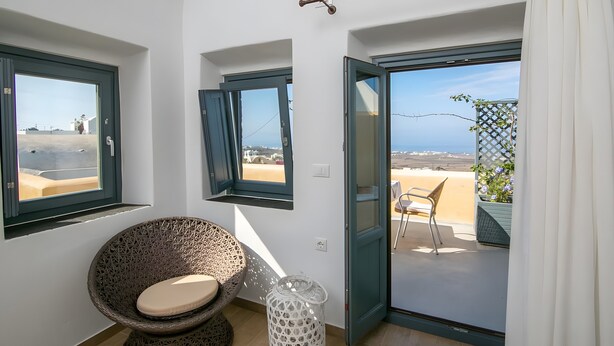 A room with a view of the beach, a wicker chair, a white trash bin, and a sliding glass door leading to an outdoor area. - Apartment in A Hotel 'Honeymoon in Finikia - Oi' with Wi-Fi and Air Conditioning (Finikia)