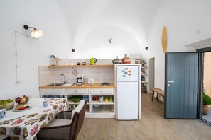 A compact kitchen with a refrigerator, a sink, and a dining area with a table and chairs. - Apartment in A Hotel 'Honeymoon in Finikia - Oi' with Wi-Fi and Air Conditioning (Finikia)