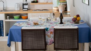 Een keuken met een eettafel, stoelen en diverse keukenapparaten.