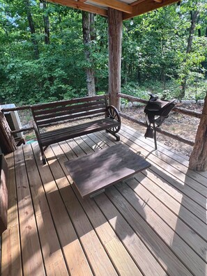 Une terrasse en bois avec un banc et un barbecue.