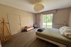 Une chambre à coucher avec un lit, un banc en bois, une chaise, un radiateur et une vue sur l’extérieur.
