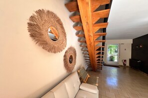 Ein modernes Interieur mit einer Holztreppe, einem weißen Sofa und dekorativen Wandspiegeln.